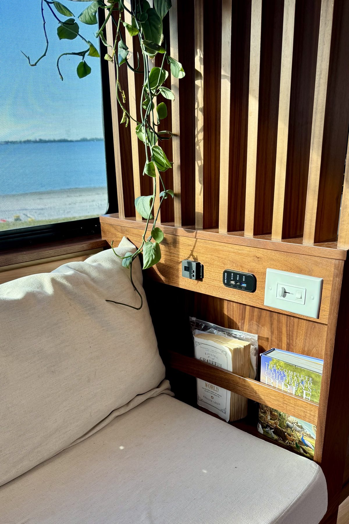 The walnut and maple slat wall behind the couch, with the lake through the window